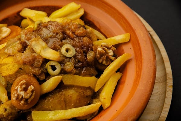 Tajine met kip, olijven, walnoten en frietjes in een aardewerken schaal