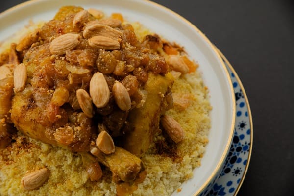 Couscous met kip, amandelen en gekarameliseerde ui op een bord met blauwe rand